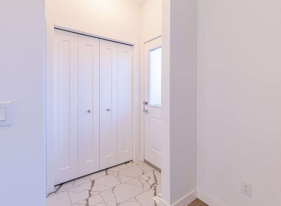 Step into this inviting entryway, featuring a sleek white door with a frosted glass panel, perfect for welcoming guests.