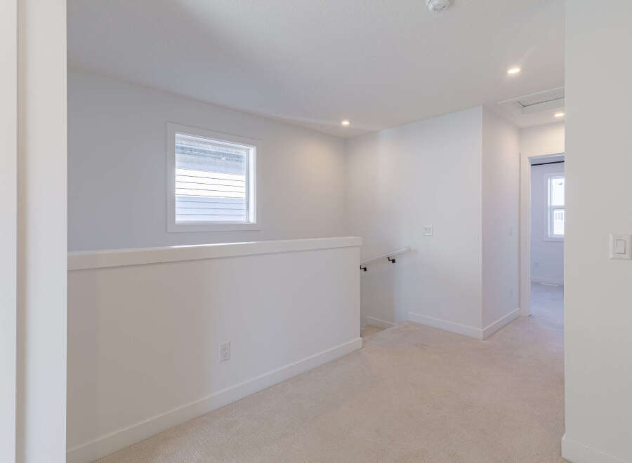 This bright and airy hallway features a modern aesthetic with clean white walls and neutral carpeting.