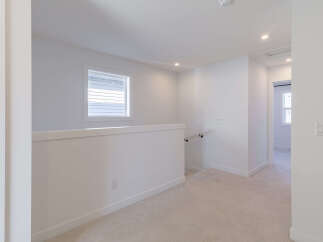 This bright and airy hallway features a modern aesthetic with clean white walls and neutral carpeting.