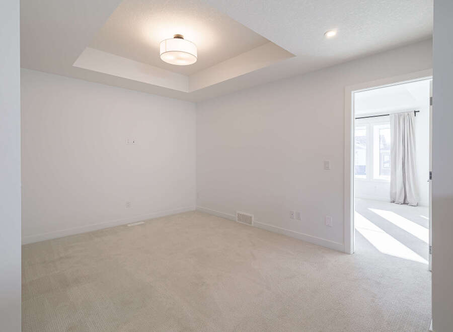 Step into this bright and airy bedroom, featuring a stunning tray ceiling with recessed lighting and a modern drum pendant light.