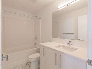 This modern bathroom features a pristine white bathtub and shower combination, complemented by sleek subway tile accents.