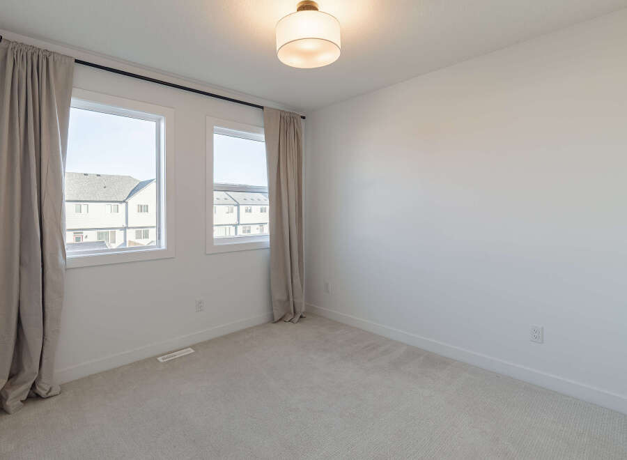 This bright and airy bedroom features two large windows that flood the space with natural light.