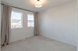 This bright and airy bedroom features two large windows that flood the space with natural light.