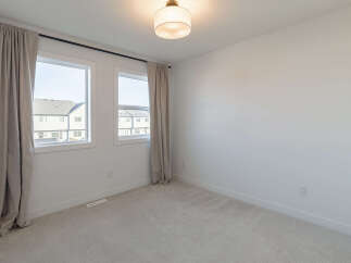 This bright and airy bedroom features two large windows that flood the space with natural light.