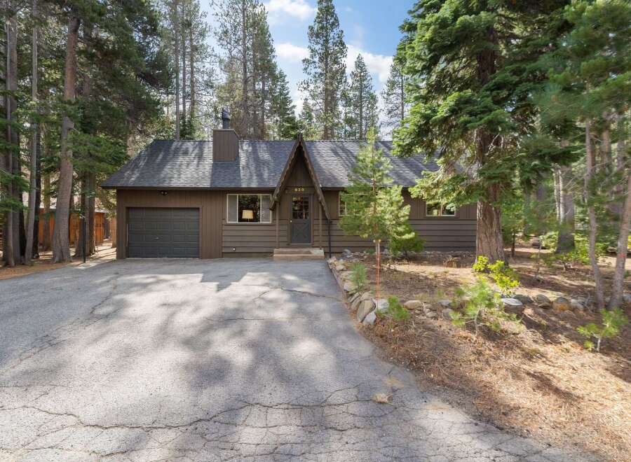 Nestled amongst tall pine trees, this charming brown home offers a serene mountain retreat.