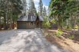 Nestled amongst tall pine trees, this charming brown home offers a serene mountain retreat.