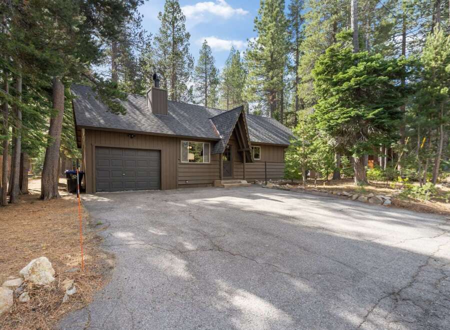 Nestled amongst tall pine trees, this charming brown home offers a serene retreat.