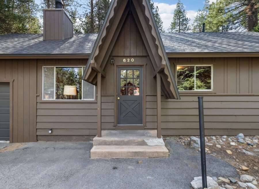 Charming A-frame home with a rustic brown exterior, featuring a welcoming covered porch with a glass-paned door and house number '620'.