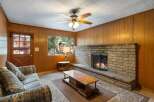 Cozy up by the stone fireplace in this inviting living room, featuring warm wood paneling and a comfortable sofa.