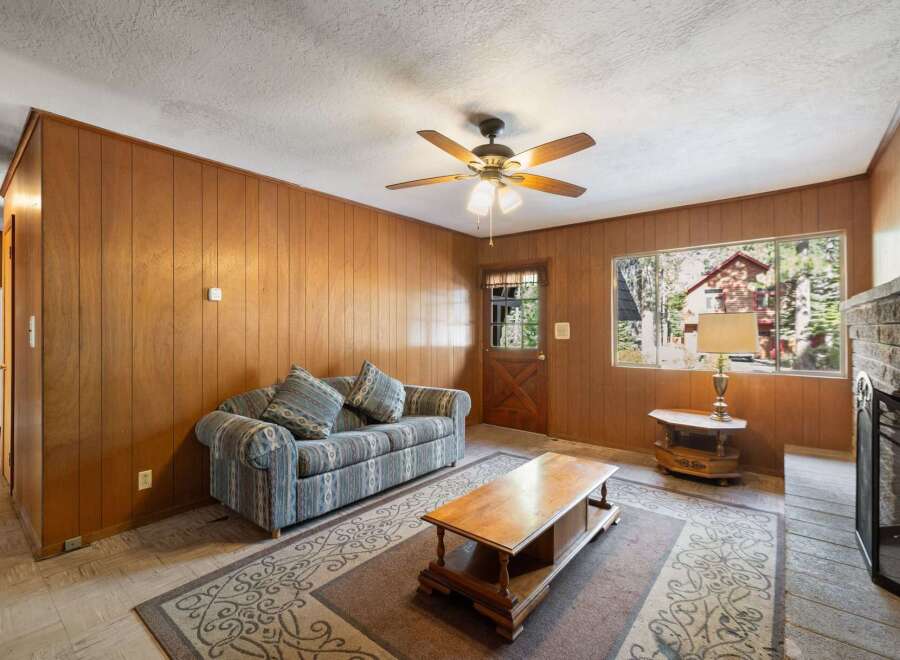 Step into this cozy living room featuring warm wood-paneled walls and a comfortable sofa perfect for relaxing.