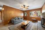 Step into this cozy living room featuring warm wood-paneled walls and a comfortable sofa perfect for relaxing.