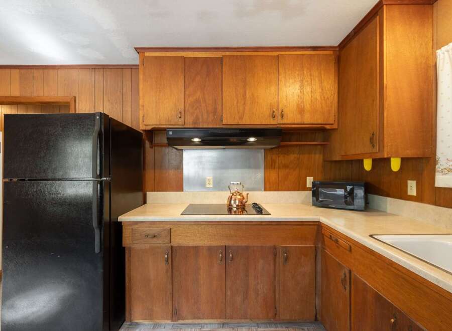 This charming kitchen features warm wood cabinetry and paneling, creating a cozy and inviting atmosphere.