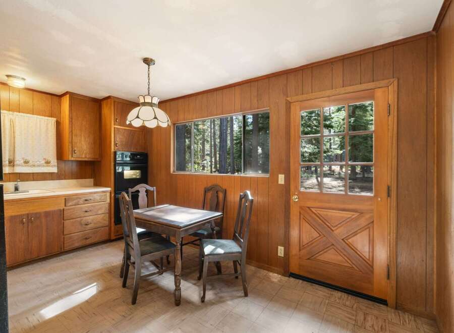 This charming kitchen features warm wood paneling and ample cabinetry, creating a cozy and functional space.