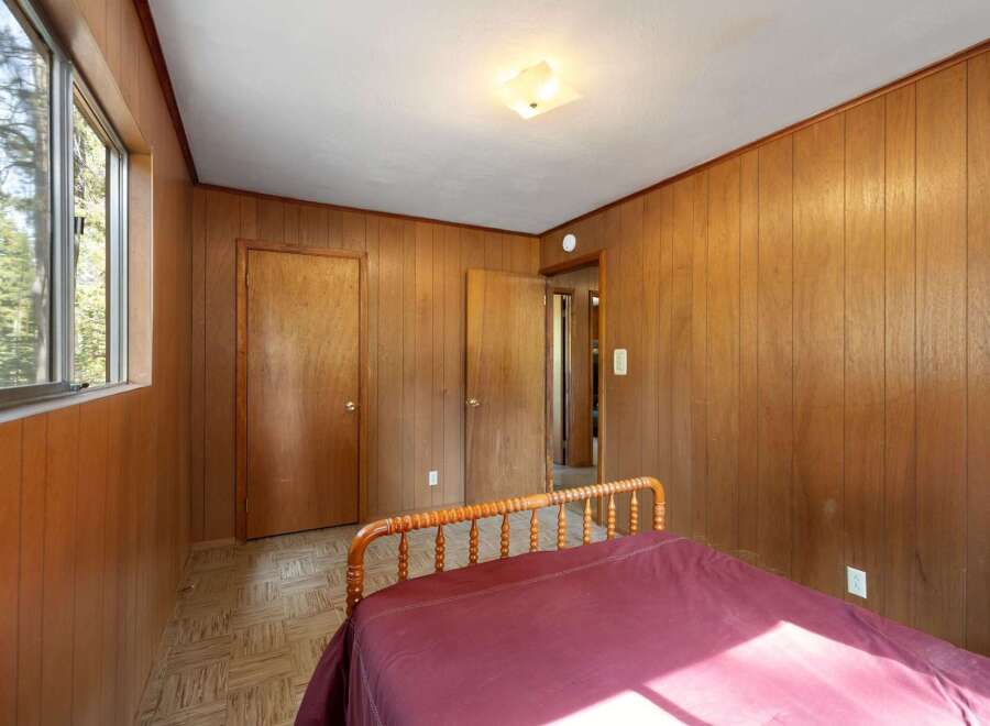 Step into a cozy retreat with this charming bedroom, featuring warm wood-paneled walls that create a rustic and inviting atmosphere.