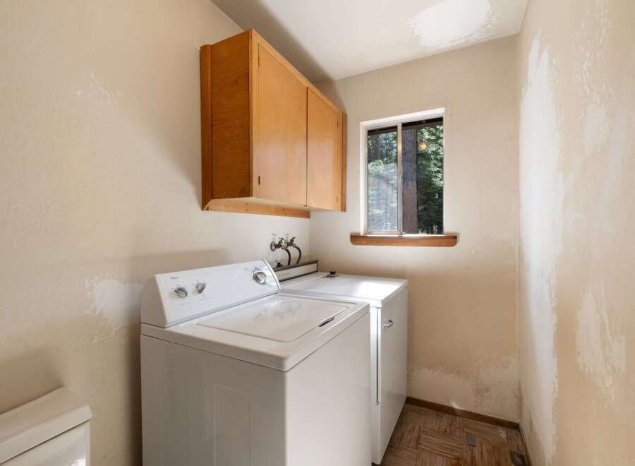 This laundry room features a white top-load washer and dryer set, perfect for handling your family's laundry needs.