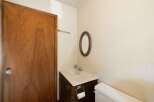 This bathroom features a classic wooden door, a vanity with a sink and mirror, and a toilet.