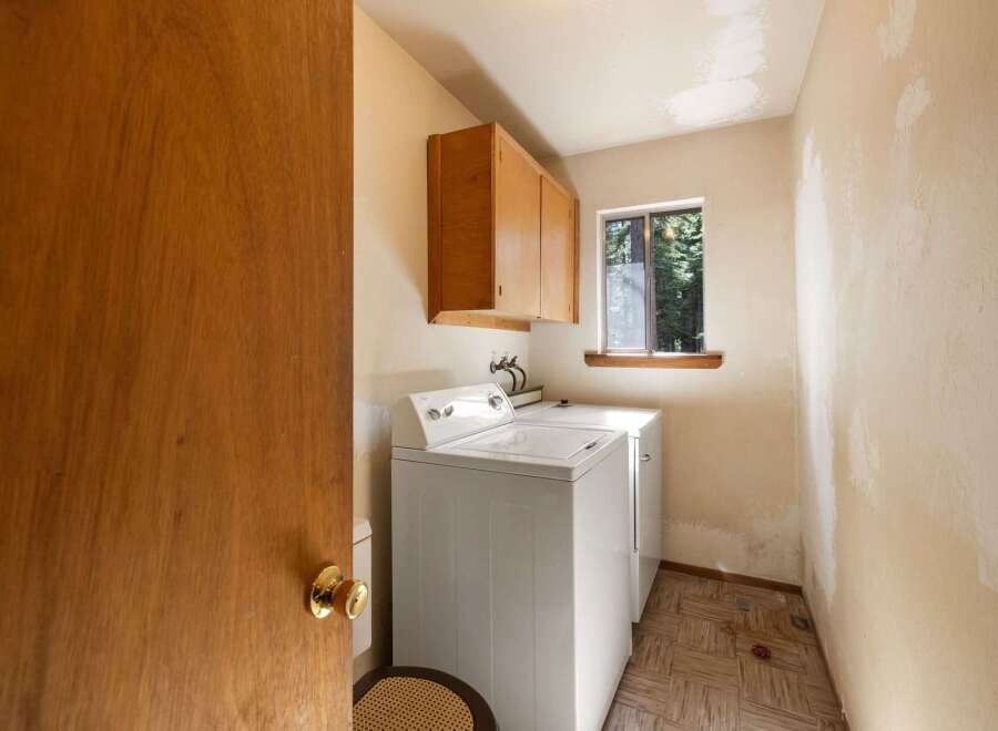 This laundry room features a white top-loading washing machine and a dryer, perfect for handling your household chores.