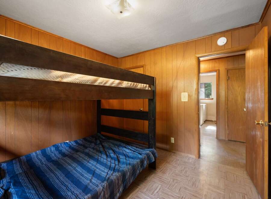 This cozy bedroom features a sturdy wooden bunk bed with blue striped bedding, perfect for accommodating guests or family.