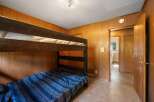 This cozy bedroom features a sturdy wooden bunk bed with blue striped bedding, perfect for accommodating guests or family.