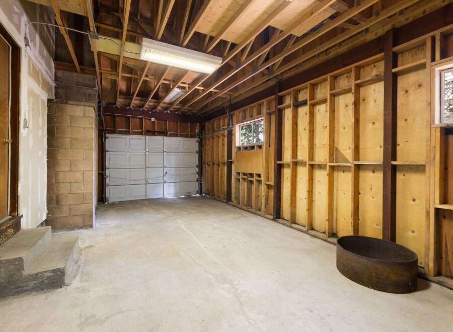 This spacious garage offers ample room for vehicles and storage, featuring a durable concrete floor and a sturdy overhead door.