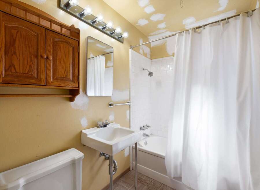 This bathroom features a classic white pedestal sink with chrome fixtures, complemented by a wooden medicine cabinet above.