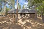 Nestled amongst tall pine trees, this charming brown home offers a serene retreat.