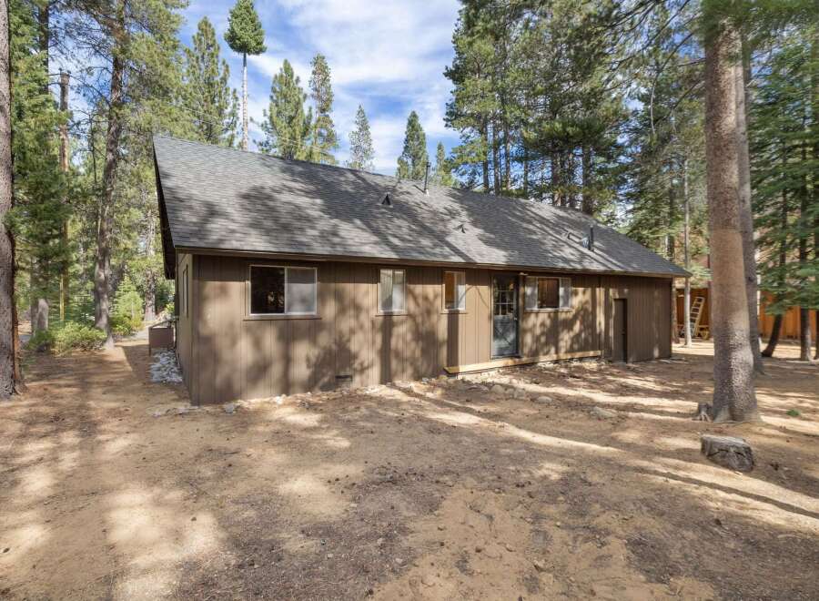 Nestled amongst tall pine trees, this charming home offers a serene retreat.