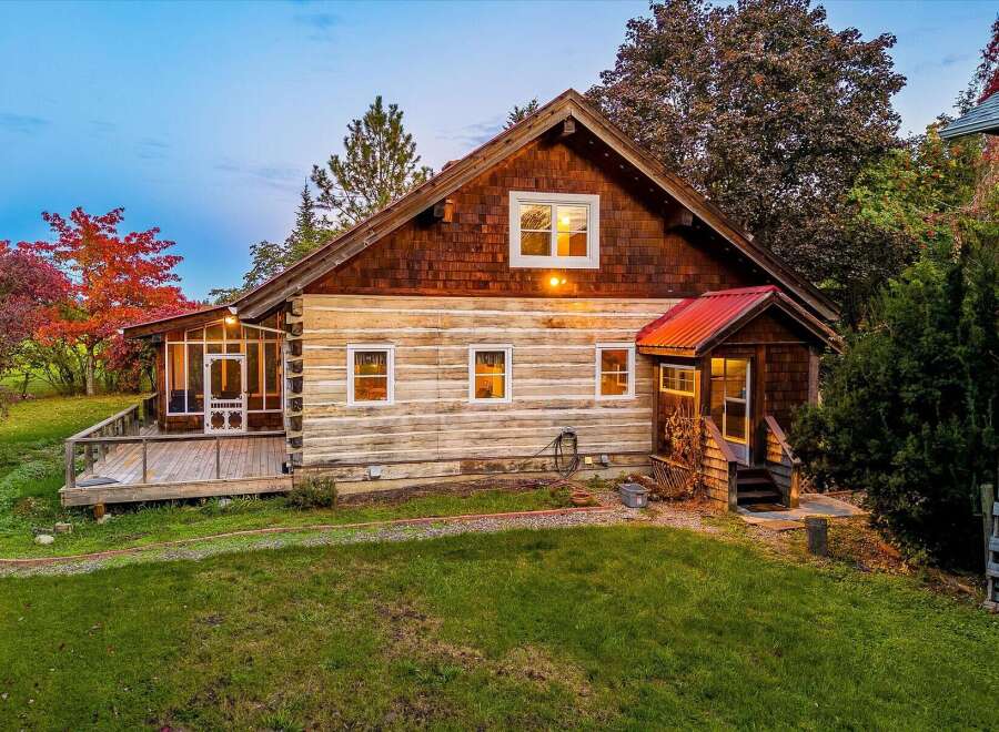 Experience rustic charm in this log cabin home, featuring a spacious wooden deck perfect for enjoying the surrounding natural beauty.