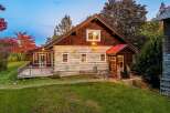 Experience rustic charm in this log cabin home, featuring a spacious wooden deck perfect for enjoying the surrounding natural beauty.