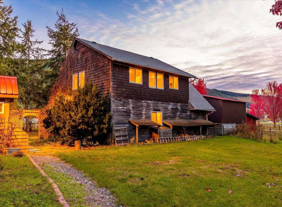 Experience rustic charm with this multi-story wooden home, featuring warm, illuminated windows that suggest a cozy interior.