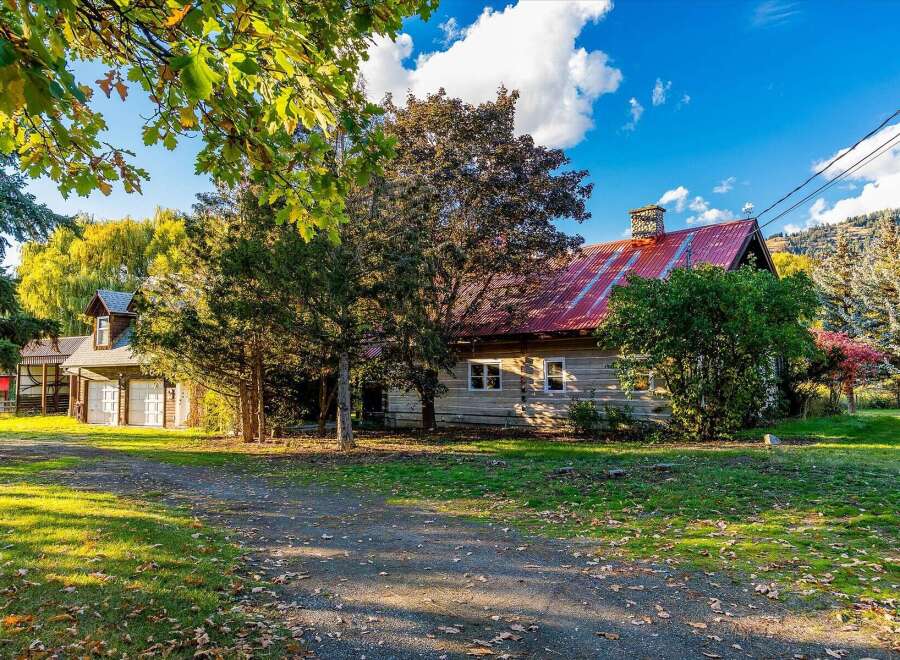 Nestled amidst a vibrant autumn landscape, this charming log cabin boasts a striking red metal roof and a classic stone chimney.