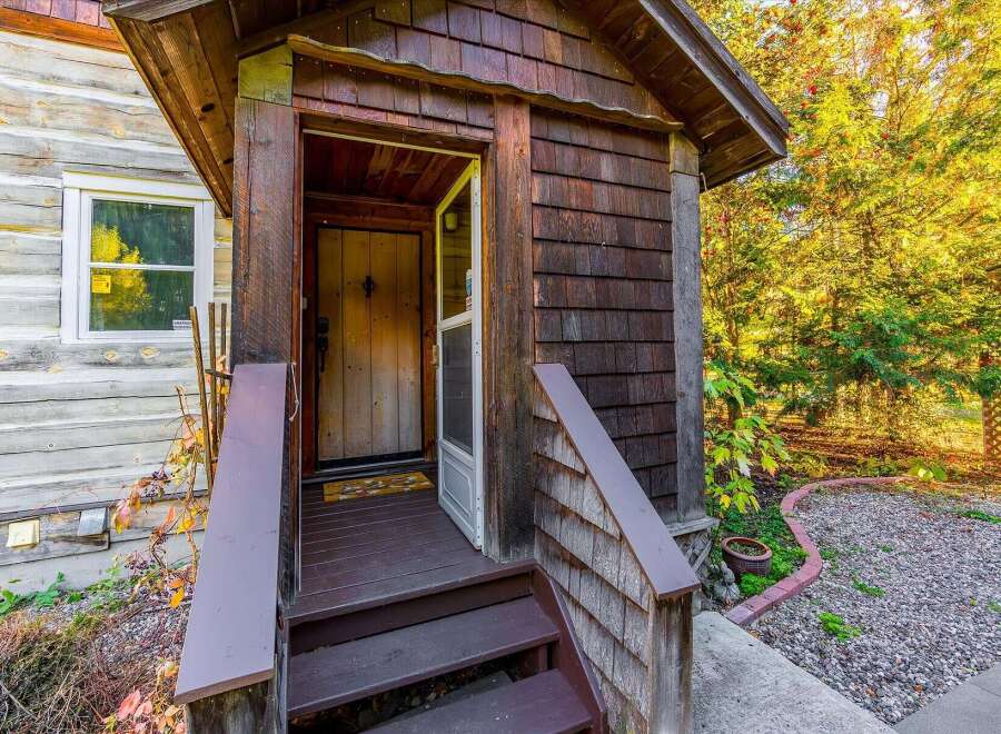 Step into this charming rustic cabin, featuring a welcoming wooden porch with a screen door leading to the interior.
