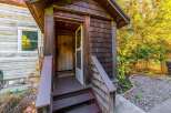 Step into this charming rustic cabin, featuring a welcoming wooden porch with a screen door leading to the interior.