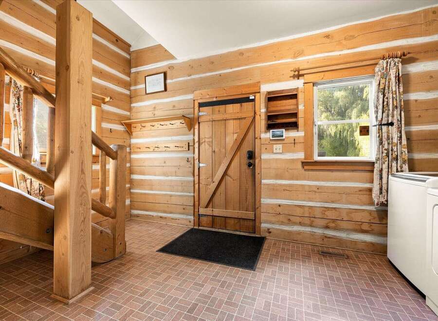 Step into this charming log cabin entryway, featuring a sturdy wooden staircase and a rustic wooden door.
