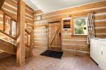 Step into this charming log cabin entryway, featuring a sturdy wooden staircase and a rustic wooden door.