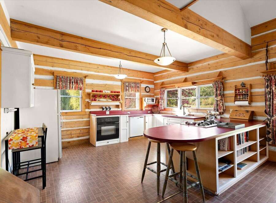 Experience rustic charm in this log cabin kitchen, featuring exposed wooden beams and log walls that create a warm, inviting atmosphere.
