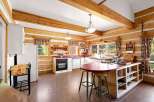 Experience rustic charm in this log cabin kitchen, featuring exposed wooden beams and log walls that create a warm, inviting atmosphere.
