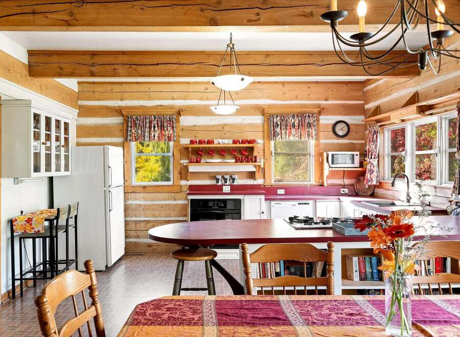 Experience rustic charm in this log cabin kitchen, featuring warm wood beams and paneling throughout.