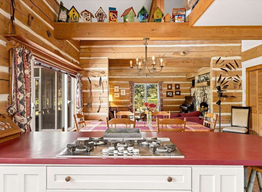 Experience rustic charm in this log cabin kitchen, featuring a gas stovetop set into a vibrant red countertop.