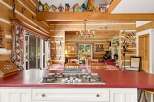 Experience rustic charm in this log cabin kitchen, featuring a gas stovetop set into a vibrant red countertop.
