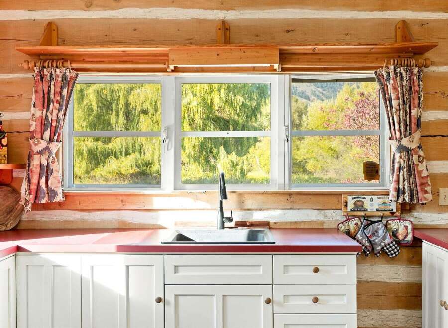This charming kitchen features white cabinetry and a red countertop, providing a bright and inviting space.