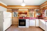 Step into this charming log cabin kitchen, featuring rustic wood paneling and cozy red countertops.