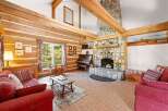 Experience rustic charm in this inviting log cabin living room, featuring a grand stone fireplace and exposed wooden beams that create a warm, cozy atmosphere.