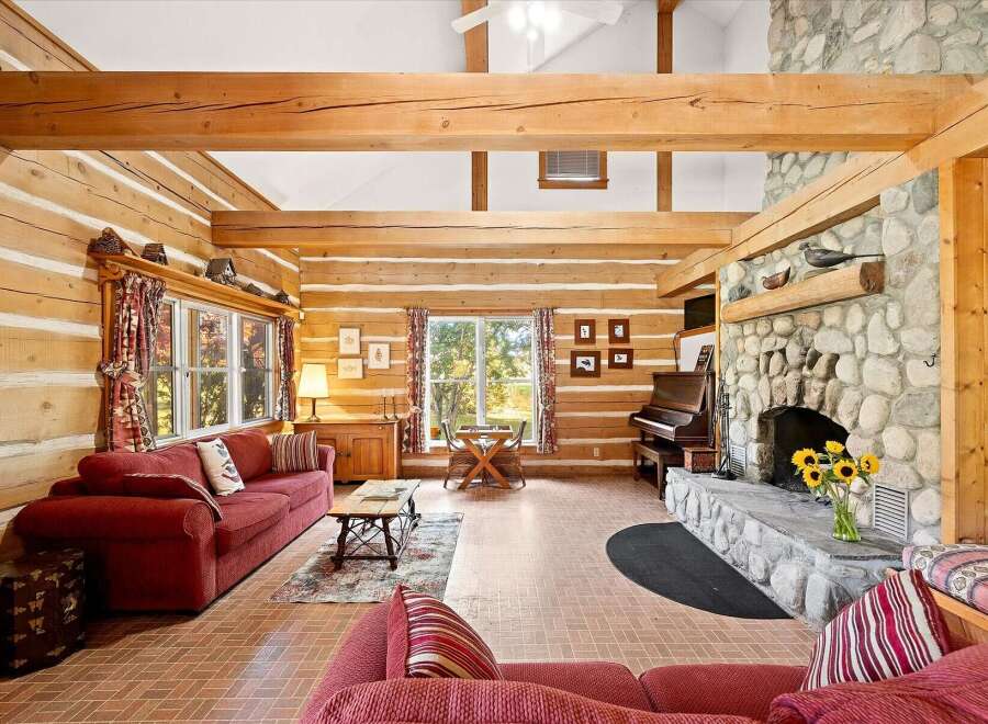 Experience rustic charm in this stunning log cabin living room, featuring exposed wooden beams and a grand stone fireplace.