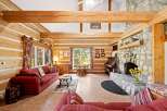 Experience rustic charm in this stunning log cabin living room, featuring exposed wooden beams and a grand stone fireplace.