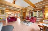 Step into this charming log cabin living room, featuring a cozy seating area with two plush red sofas and a rustic coffee table.