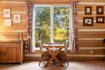Experience rustic charm in this cozy log cabin featuring a dedicated chess table by the window, perfect for enjoying scenic views during a game.