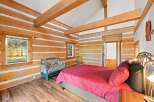 Experience rustic charm in this log cabin bedroom, featuring exposed wooden beams and a cozy, inviting atmosphere.