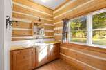 Experience rustic charm in this log cabin bathroom, featuring a functional vanity with ample storage and a bright, natural light-filled space.