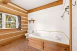 Experience rustic charm in this log cabin bathroom, featuring a spacious corner jetted tub with a warm wooden surround.